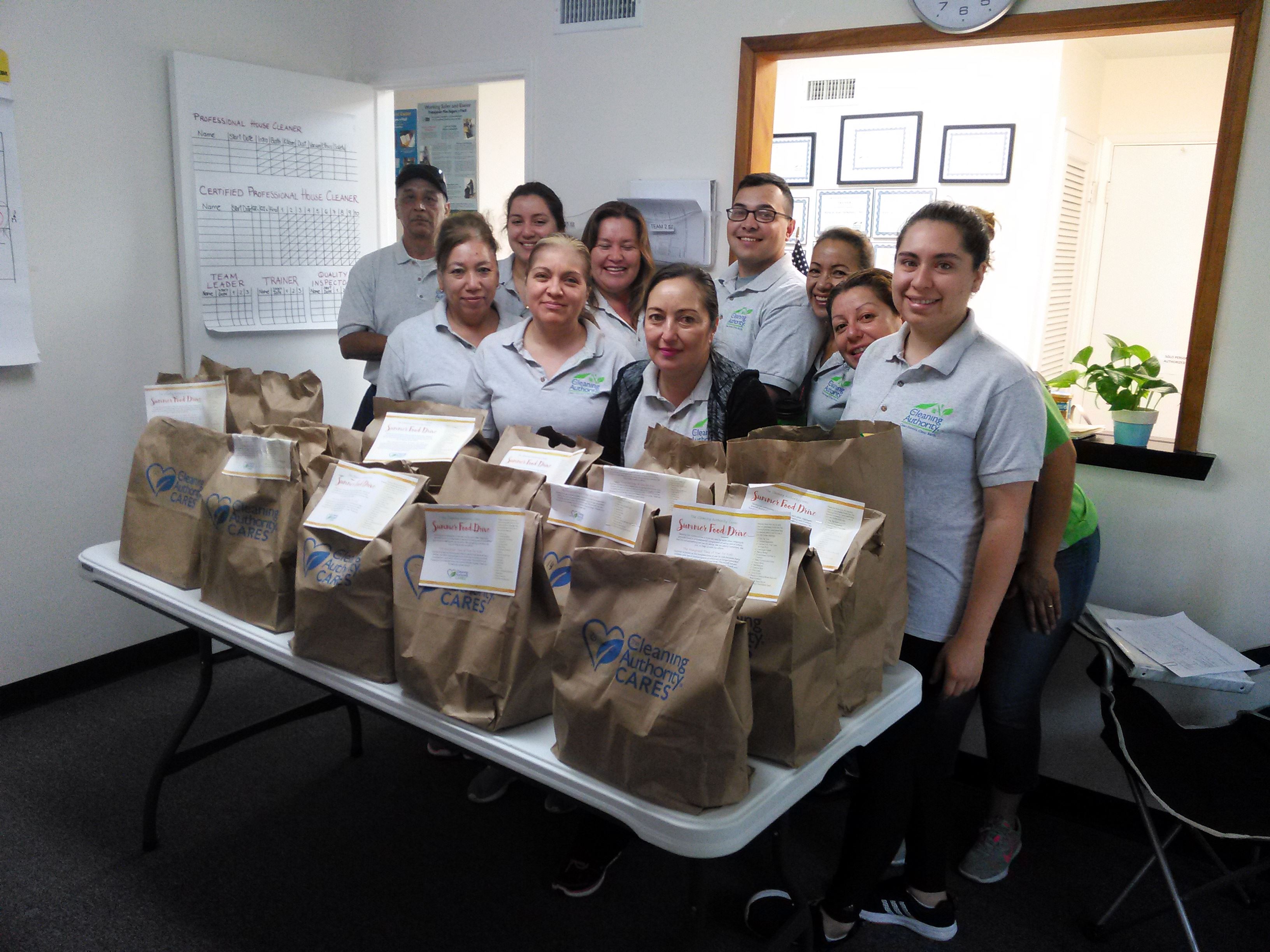 The TCA San Diego team stands in their office with donations collected for a local charity.